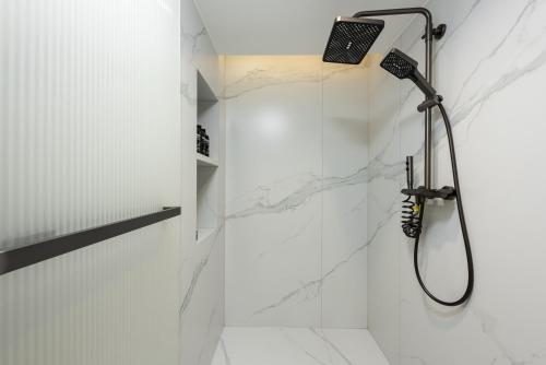 a bathroom with a shower with white marble walls at Leshan Manfu Hotel in Leshan