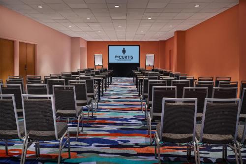a room with rows of chairs in front of a screen at the Curtis Denver - A DoubleTree by Hilton Hotel in Denver