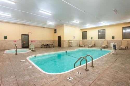 a large pool in a room with chairs and a table at La Quinta Inn & Suites - New River Gorge National Park in Summersville