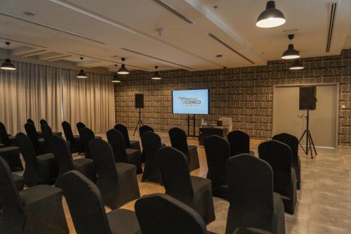 a room with chairs and a screen with a presentation at VOGO Grand Hotel Formerly Best Western Plus Hotel Dubai Academic City in Dubai