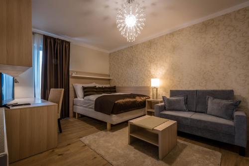 Vila Monika في Tvrdošovce: غرفة نوم بسرير واريكة وثريا