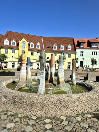 a fountain in the middle of a courtyard with houses at Ferienidyll an der Recknitz in Tessin