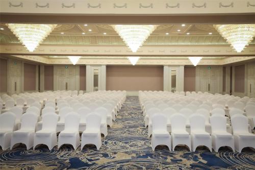an empty auditorium with white chairs and tables at Kempinski Al Othman Hotel Al Khobar in Al Khobar