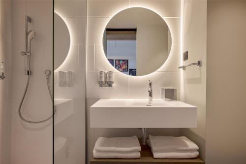 a bathroom with a sink and a mirror at Hampton By Hilton Lyon Airport in Colombier-Saugnieu