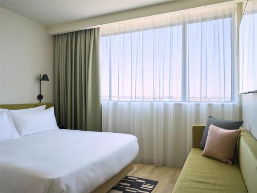 a hotel room with a bed and a large window at Hampton By Hilton Lyon Airport in Colombier-Saugnieu