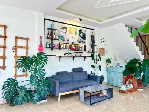 a living room with a blue couch and plants at Cloud River Homestay in Da Lat