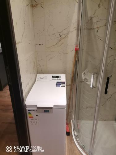 a white refrigerator in a room with a shower at Super studio w centrum miasta Hoza 9a in Otwock