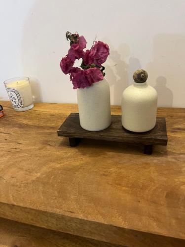 two white vases with flowers on a wooden table at Makasi Zanzi - Minimalist apartment in Jambiani Village in Jambiani