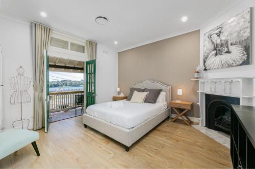a bedroom with a white bed and a fireplace at Waterfront Stylish & Charming City Retreat in Sydney