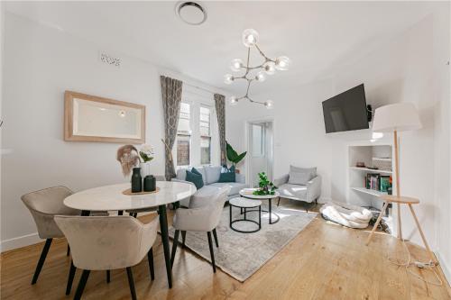 a white living room with a table and chairs at Waterfront Stylish & Charming City Retreat in Sydney