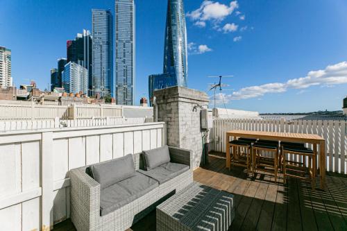 a patio with a couch and a table on a balcony at Waterfront Stylish & Charming City Retreat in Sydney