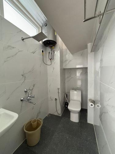 a bathroom with a white toilet and a sink at Kerphida B&B in Shillong