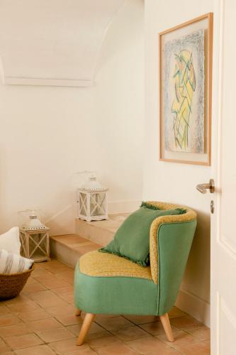a living room with a green chair and stairs at Arkhé Hotel Boutique Pals in Pals