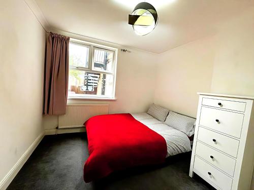 a bedroom with a red bed and a window at Cosy City Hideout in London