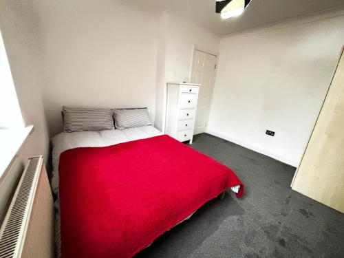 a bedroom with a red blanket on a bed at Cosy City Hideout in London