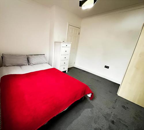 a bedroom with a red blanket on a bed at Cosy City Hideout in London