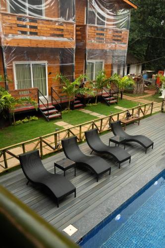 a group of chairs sitting next to a swimming pool at Tranquillo By The Beach in Candolim