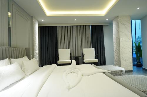 a bedroom with a large white bed with two chairs at The Khushi Hotel And Resorts in Murree