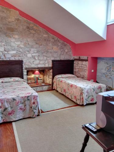 a bedroom with two beds and a stone wall at Posada Valle De Guriezo in Ríoseco