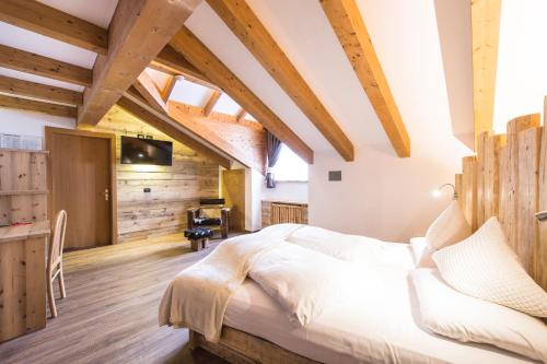 a bedroom with a large bed in a room with wooden ceilings at Alpstyle Hotel Albolina Wellness & Beauty in Canazei