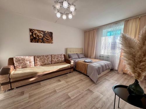 a living room with a couch and a bed at Квартира рядом с Усолкой Сатпаева 348 in Pavlodar