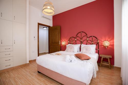 a bedroom with a large white bed with red walls at Akl - Chic Apartments & Balconies in Batroun in Batroûn