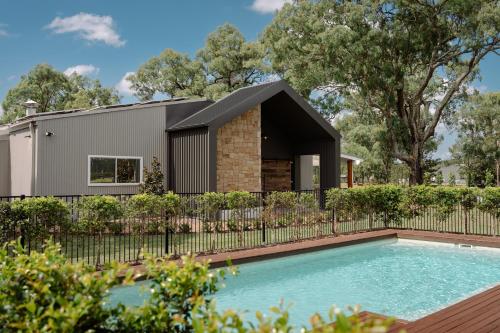 a house with a swimming pool in front of a fence at Emma's Cottage Vineyard in Lovedale