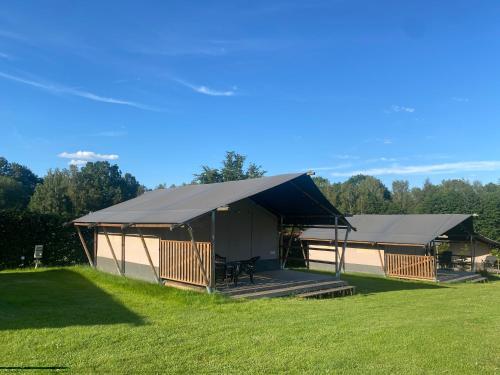 a large building with a black roof on a grass field at Kemp Sluknov- Glamping in Děčín