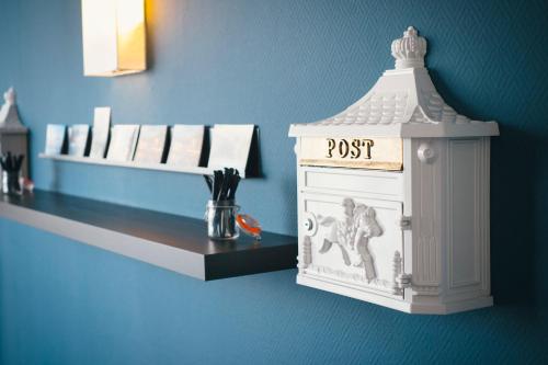 a white post box on a blue wall with a shelf at Vienna House Easy by Wyndham Neckarsulm in Neckarsulm