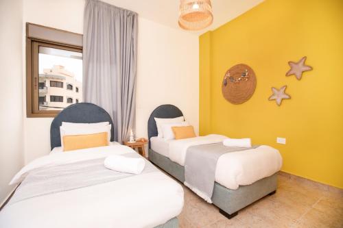 two beds in a room with yellow walls at Akl - Chic Apartments & Balconies in Batroun in Batroûn