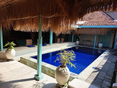 a resort with a swimming pool and a straw umbrella at Lavender Villa 7 Moon House in Kuta