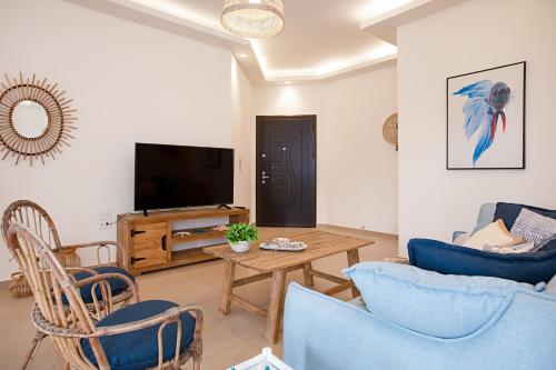 a living room with a tv and a table and chairs at Akl - Chic Apartments & Balconies in Batroun in Batroûn