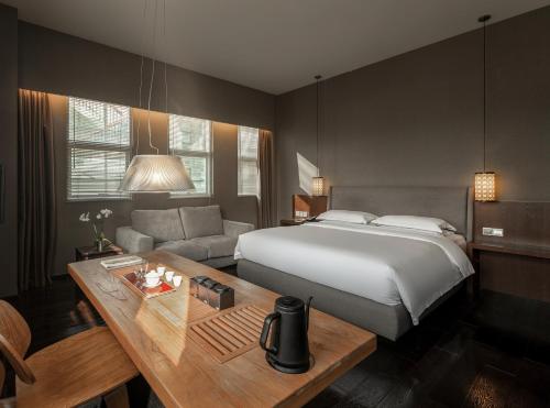 a bedroom with a bed and a table and a couch at The Hermitage Hotel in Chengdu