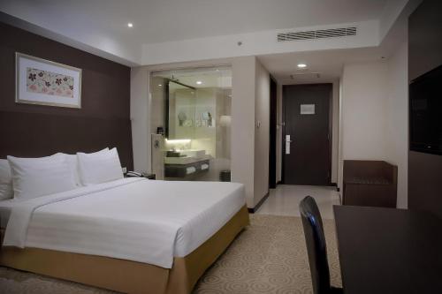 a hotel room with a bed and a bathroom at The Alana Surabaya in Surabaya