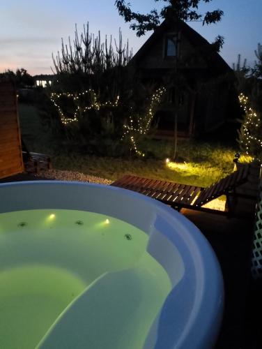 a jacuzzi tub in a yard with a house at Domek pod czerwonym Dębem in Stare Kiejkuty
