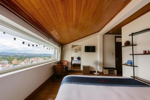 a bedroom with a large bed and a large window at Cosy Hotel & Apartment Dalat in Da Lat