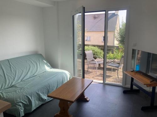 a bedroom with a bed and a table and a sliding glass door at accommodation for 4 people maximum in Guignen
