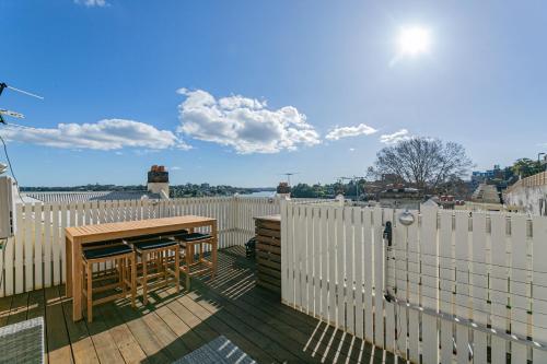 a deck with a wooden table and a wooden fence at Waterfront Stylish & Charming City Retreat in Sydney