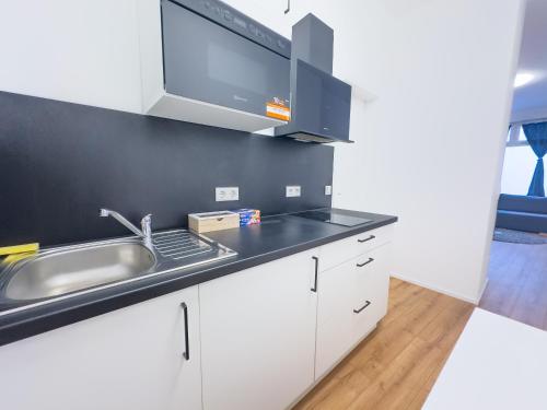 a kitchen with white cabinets and a sink at Moderne Wohnung im Zentrum der Altstadt - Altbau Flair, WLAN in Ingolstadt