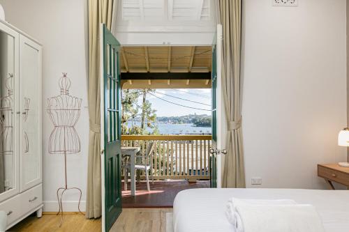 a bedroom with a bed and a door to a balcony at Waterfront Stylish & Charming City Retreat in Sydney