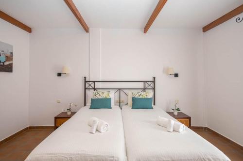 a bedroom with two beds with white sheets and blue pillows at Lightbooking Las Breñas Garden con piscina in Breña Baja
