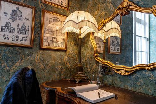 a lamp on a table with a book and a mirror at Melville Castle Hotel in Edinburgh