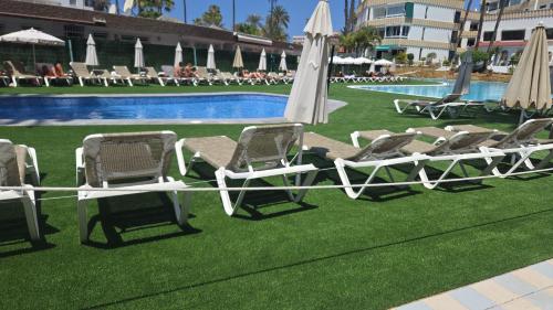 a group of lawn chairs and umbrellas next to a pool at Loft Koka Alto in San Bartolomé de Tirajana