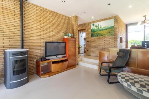 a living room with a tv and a brick wall at Can Noguer Casa con piscina y jardín in Bescanó