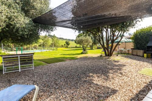 a picnic table and a bench in a park at Can Noguer Casa con piscina y jardín in Bescanó