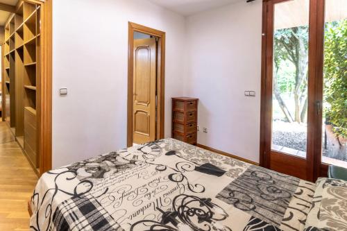 a bedroom with a bed with a black and white comforter at Can Noguer Casa con piscina y jardín in Bescanó