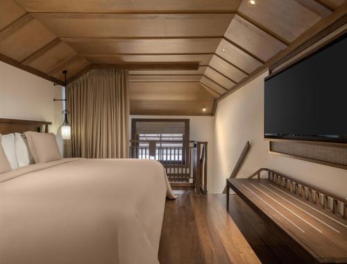 a bedroom with a large bed and a flat screen tv at Paradisus by Meliá Bali in Nusa Dua