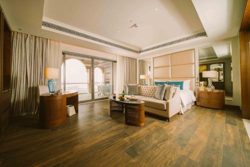 a room with a bed and a couch and a table at Royal Saray Resort in Manama