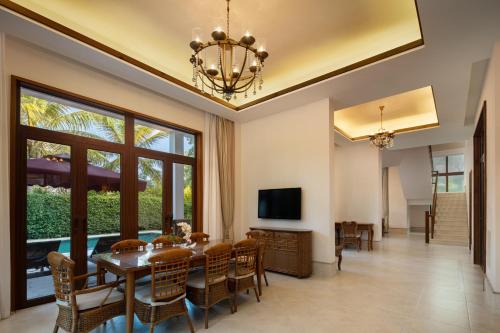 a dining room with a table and chairs and a television at Sanya Nanshan Leisure Club Seaview Hotel in Sanya
