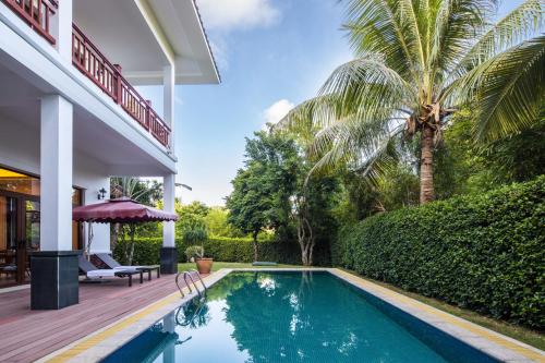 a swimming pool in the backyard of a house with a palm tree at Sanya Nanshan Leisure Club Seaview Hotel in Sanya